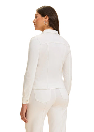 Woman wearing a white blazer and pants against a beige background