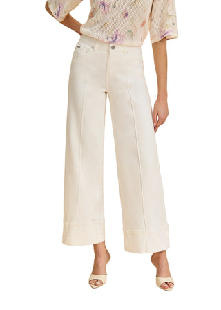 Person wearing white wide-leg pants and a patterned top on a beige background