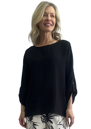 Woman wearing a black top and patterned pants against a white background