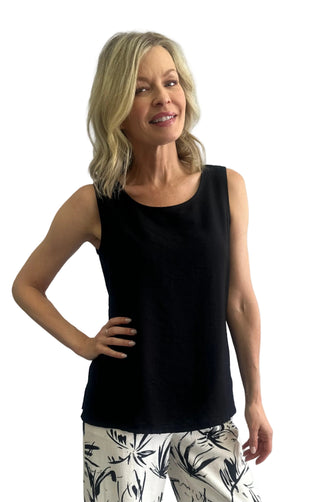 Woman wearing a black sleeveless top and patterned pants against a white background