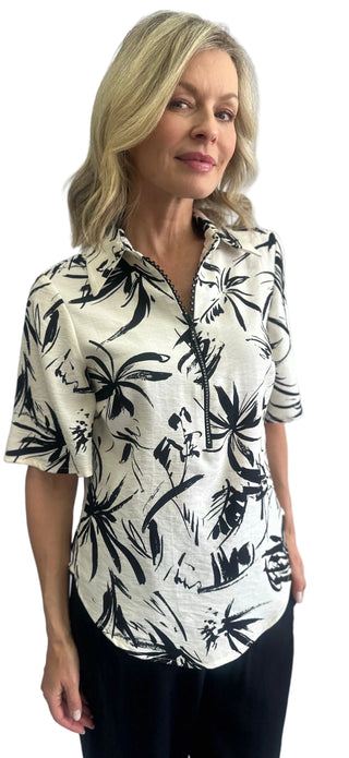 Woman wearing a black and white floral patterned shirt against a plain background