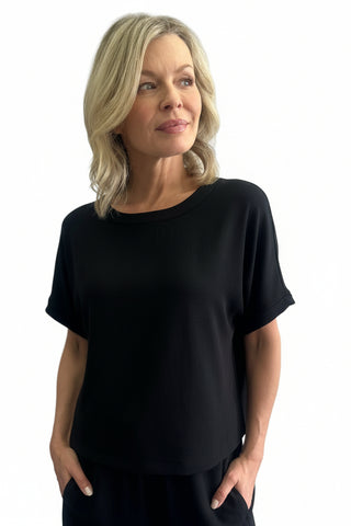 Woman wearing a black and white floral patterned top against a plain background