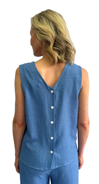 Woman wearing a blue checkered sleeveless top with buttons against a plain background