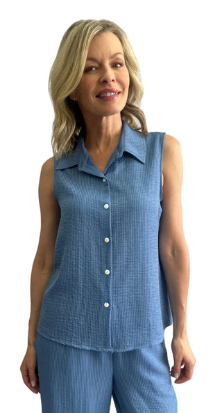 Woman wearing a blue sleeveless checkered top and pants against a white background