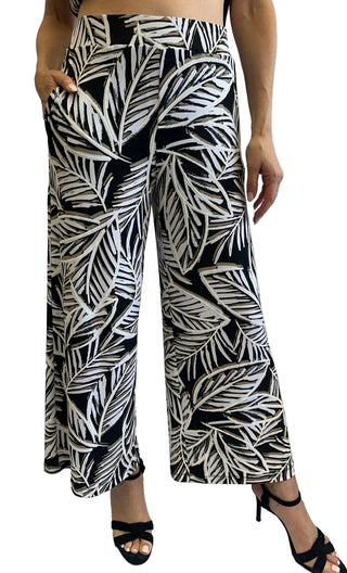 Person wearing black and white leaf-patterned pants on a white background
