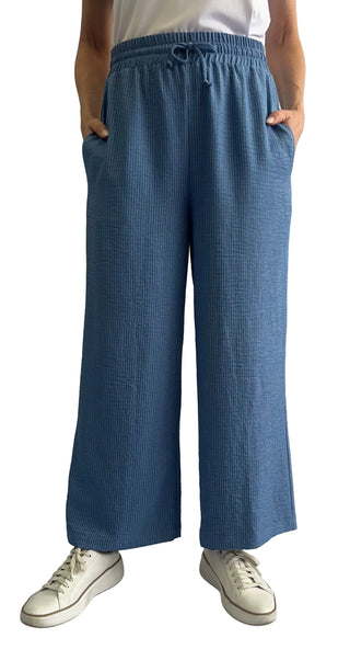 Person wearing blue checkered pants and white sneakers on a plain background