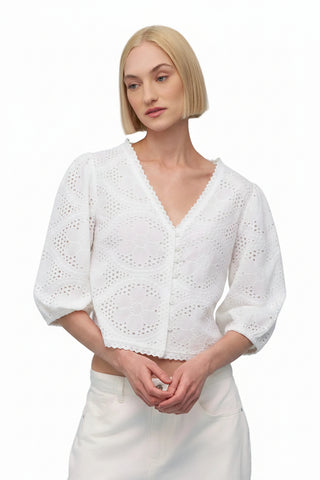 Woman wearing a pink lace top against a light blue background