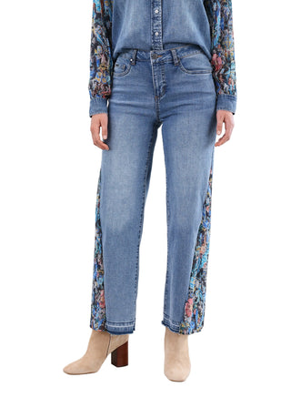 Person wearing blue jeans with floral patterns on a plain background