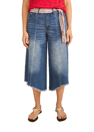 Person wearing blue denim culottes on a beige background