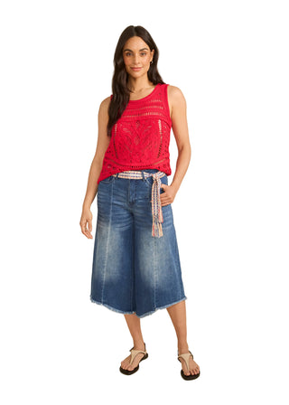 Woman wearing a red sleeveless top and blue denim skirt on a beige background