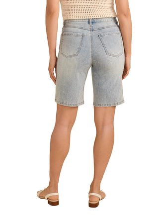 Person wearing light blue denim shorts on a beige background