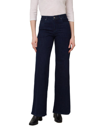 Person wearing dark blue flared jeans on a plain background
