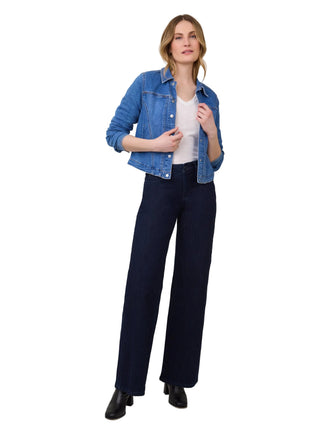 Woman wearing a blue denim jacket and navy pants on a white background