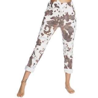 White pants with brown abstract pattern worn by a person on a white background with 'Roma' branding.