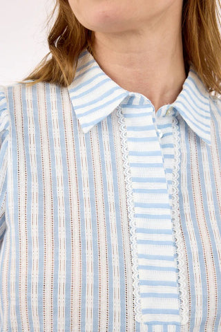 Close-up of a person wearing a blue and white striped shirt with lace details.