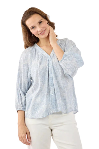 Woman wearing a light blue patterned blouse against a white background