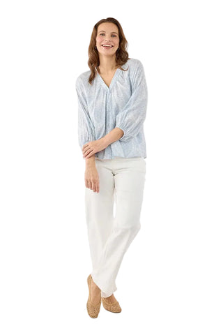 Woman wearing a light blue striped blouse and white pants on a white background