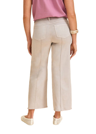 Person wearing light gray pants and a pink top on a beige background