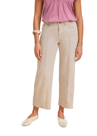 Woman wearing light gray pants and a pink top on a beige background