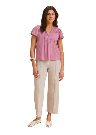 Woman wearing a pink blouse and beige pants on a beige background