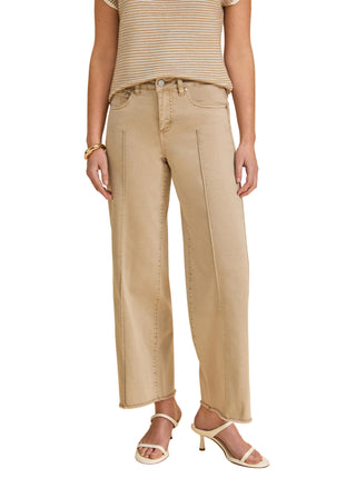 Person wearing beige pants and a striped top on a beige background