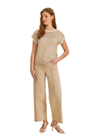 Woman wearing a beige top and pants on a beige background