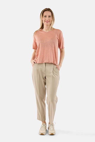 Woman wearing a pink top and beige pants on a white background