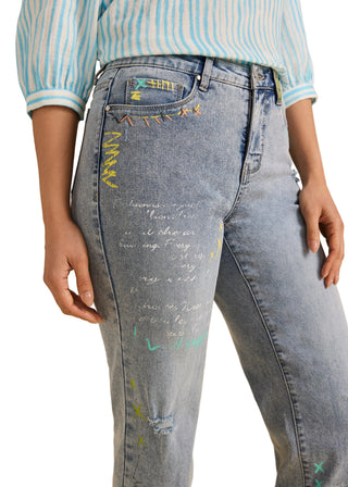 Person wearing light blue jeans with text and star designs on a beige background