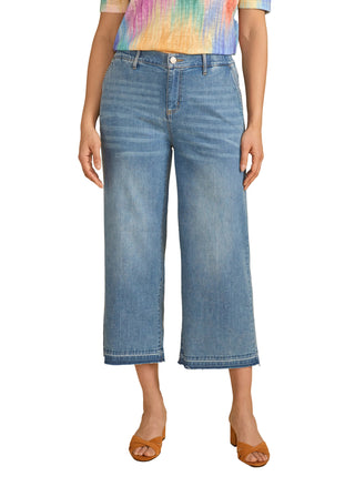 Person wearing blue jeans and a tie-dye shirt on a beige background