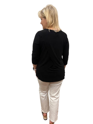 Person wearing a black top and white pants standing in front of a mirror.