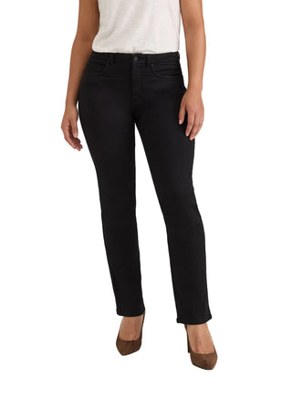 A model wearing black slim-fit ankle-length jeans, styled with a white top and brown pointed-toe heels, photographed against a seamless light gray studio background.