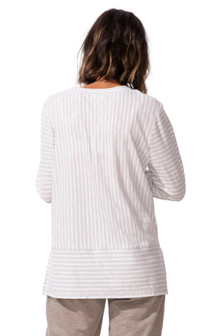 Person wearing a white ribbed sweater and light-colored pants against a white background