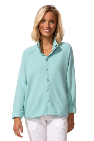 Woman wearing a light blue button-up shirt against a white background