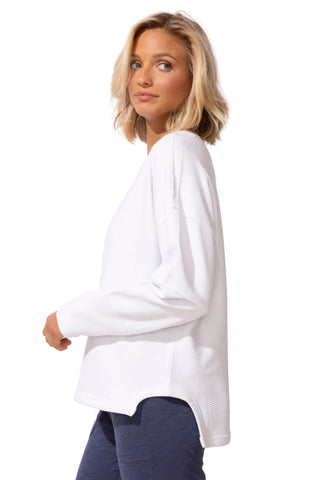 Woman wearing a white blouse with long sleeves on a plain background