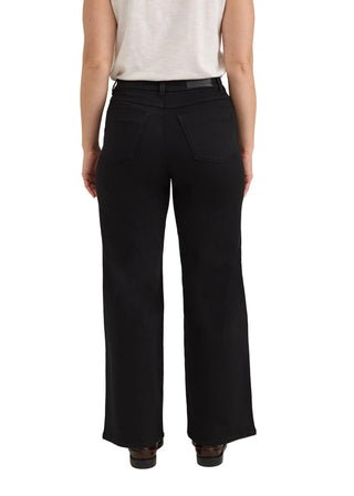 A model shown from the back wearing black wide-leg cropped pants, a light beige sleeveless top, and dark brown shoes against a neutral light gray studio background.