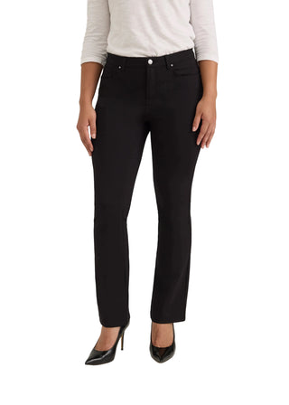 A model wearing black slim-fit ankle-length pants, a white long-sleeve top, and black pointed-toe heels, standing against a light gray studio background.