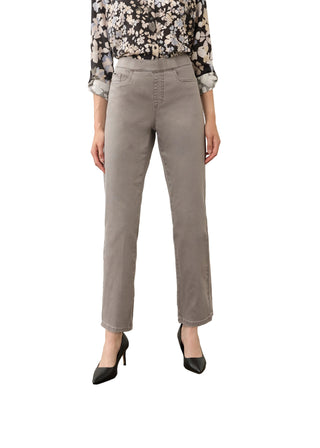 A model is shown from the waist down wearing high-waisted, straight-leg gray pants, a black and white floral blouse, and black pointed-toe heels, standing on a concrete floor against a plain off-white wall.
