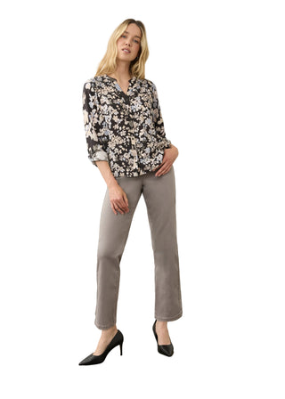 A woman modeling a black and white floral long-sleeve blouse paired with light gray straight-leg trousers and black pointed-toe heels, standing against a neutral studio backdrop.
