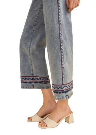 Denim pants with decorative hem on a beige background