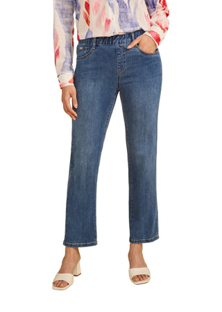 Person wearing blue jeans and a colorful top on a beige background