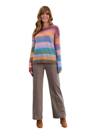 Woman wearing a colorful striped sweater and brown pants against a white background