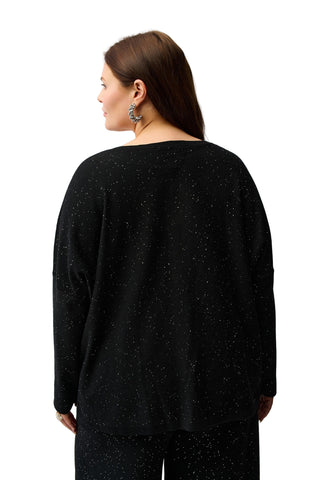 Woman wearing a black speckled sweater against a white background