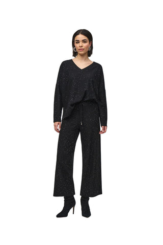 Woman wearing a black outfit with wide-leg pants on a white background