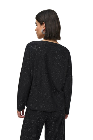 Person wearing a black speckled outfit on a white background