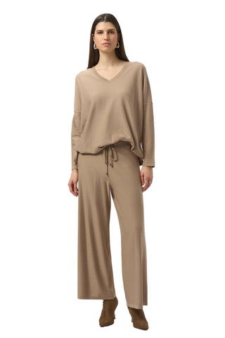 Woman wearing a beige outfit with a V-neck top and wide-leg pants on a white background