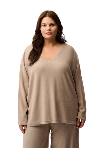 Woman wearing a beige long-sleeve top and pants on a white background