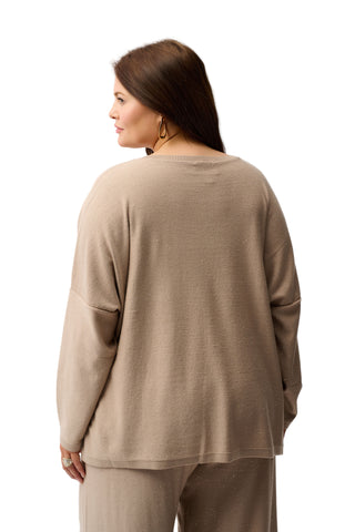Woman wearing a beige long-sleeve top and pants on a white background