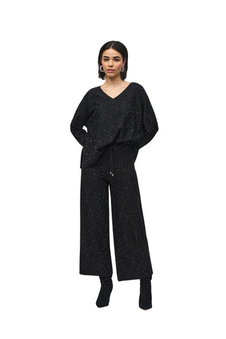 Woman wearing a black outfit with wide-leg pants on a white background