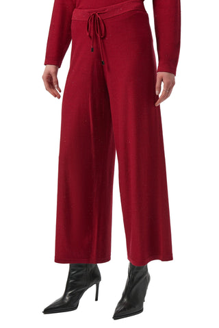 Red outfit with wide-leg pants and black high-heeled boots on a white background