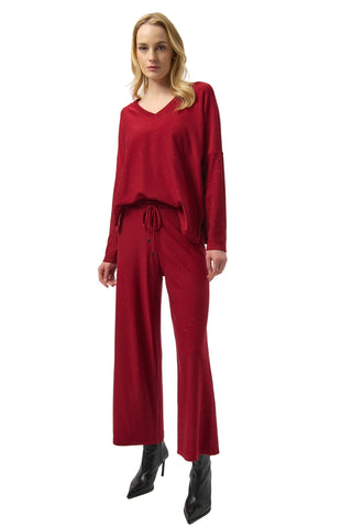 Woman wearing a red outfit with wide-leg pants on a white background